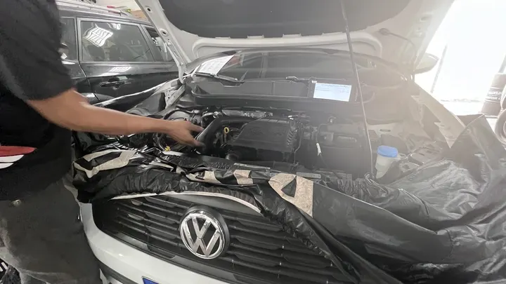 Mecânico trabalhando no motor de um Volkswagen com o capô aberto
